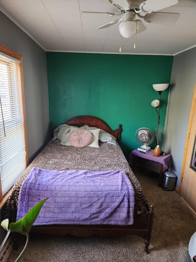 carpeted bedroom with crown molding and a ceiling fan