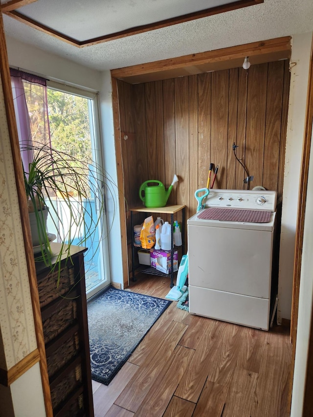 laundry room with laundry area, wood finished floors, a textured ceiling, and washer / dryer