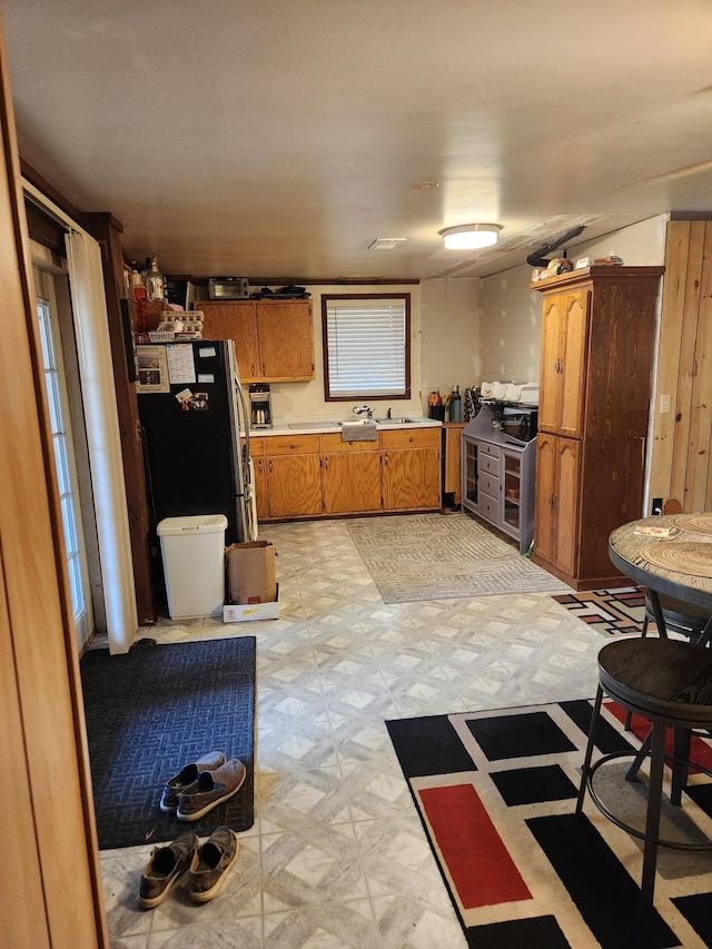 kitchen with brown cabinets, light countertops, freestanding refrigerator, and light floors