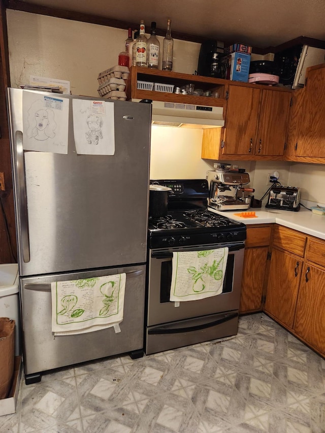 kitchen with gas stove, under cabinet range hood, freestanding refrigerator, and light floors