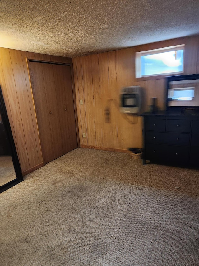 carpeted bedroom featuring a textured ceiling, a closet, wood walls, and heating unit
