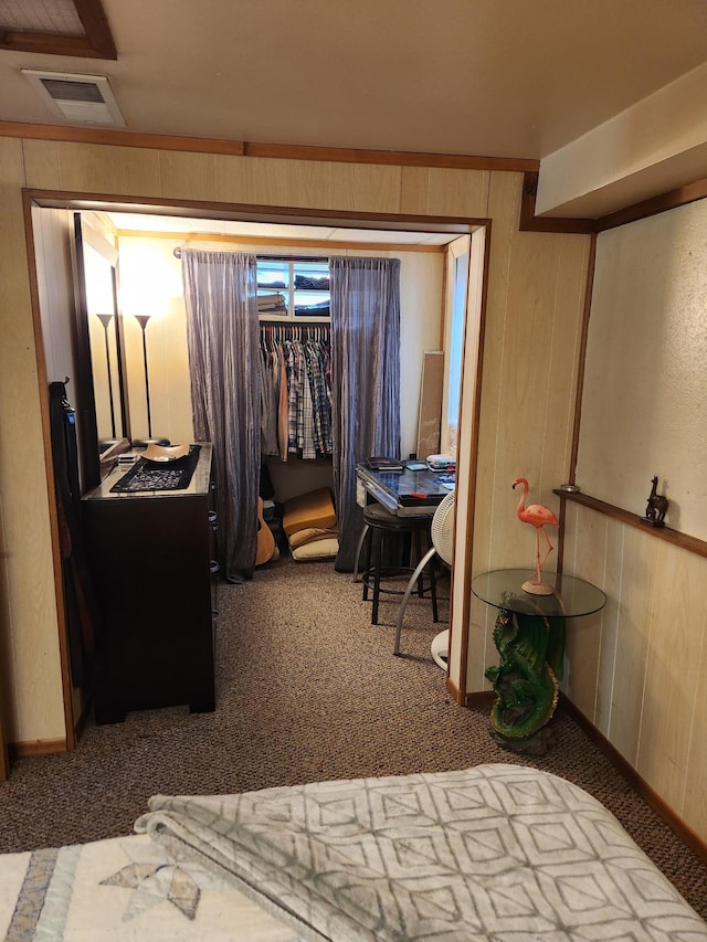 carpeted bedroom featuring wooden walls and visible vents