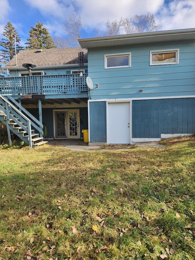 rear view of house with stairs, a deck, and a lawn