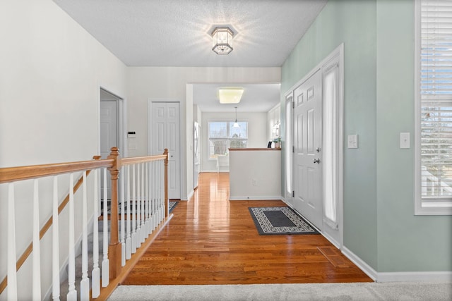 foyer featuring a textured ceiling, baseboards, and wood finished floors