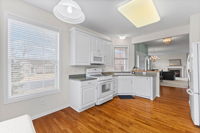 kitchen with white appliances, white cabinetry, a peninsula, and open floor plan