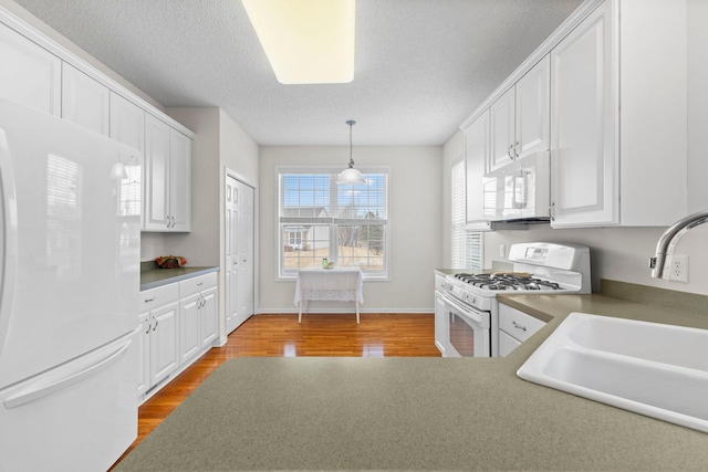 kitchen featuring white appliances, a sink, white cabinetry, and light wood-style floors