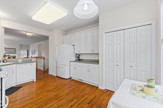 kitchen with white appliances, white cabinetry, light wood finished floors, and light countertops