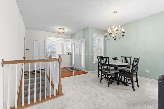 dining space with carpet floors, a notable chandelier, a textured ceiling, and baseboards