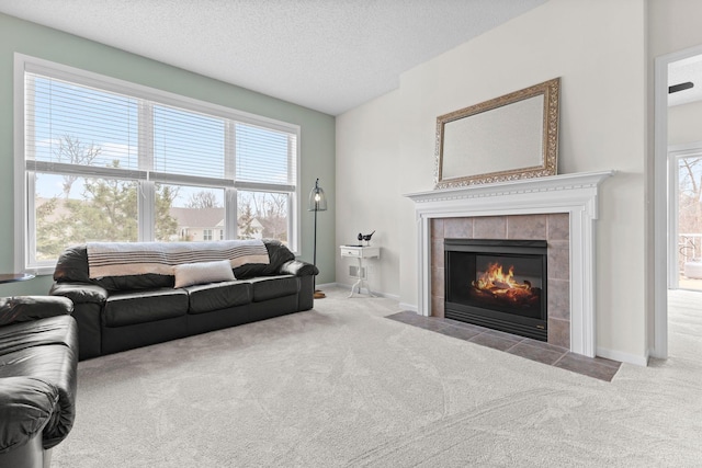 living room featuring carpet, plenty of natural light, a textured ceiling, and a tiled fireplace