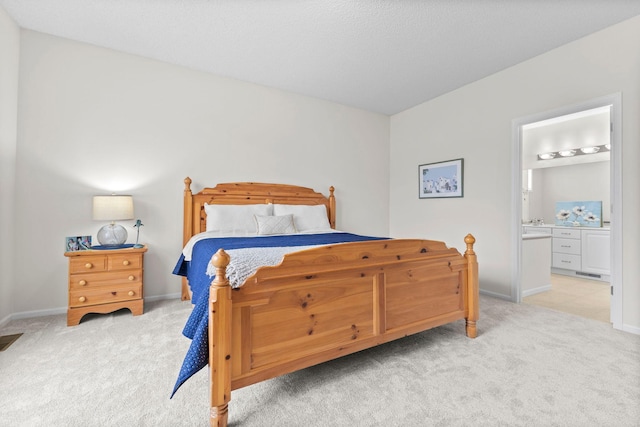 bedroom with baseboards, connected bathroom, and light colored carpet