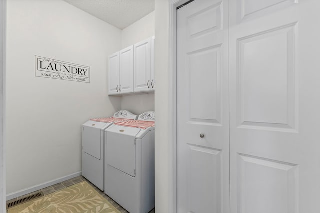 laundry area with washing machine and clothes dryer, cabinet space, visible vents, a textured ceiling, and baseboards