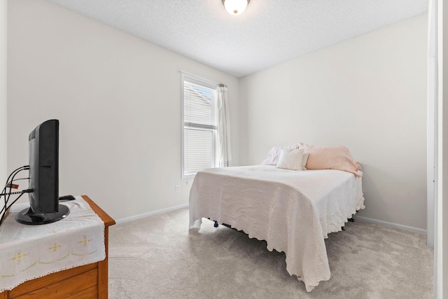 bedroom featuring light carpet, a textured ceiling, and baseboards