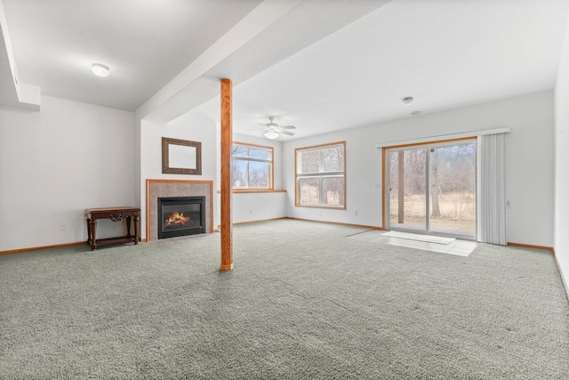 unfurnished living room featuring a tiled fireplace, carpet flooring, and baseboards