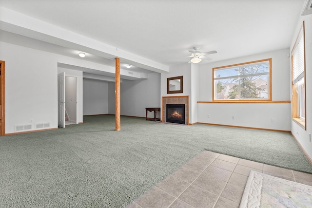 unfurnished living room featuring carpet floors, a tile fireplace, visible vents, and baseboards