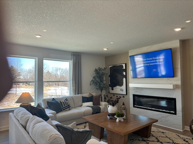 living area with recessed lighting, a glass covered fireplace, a textured ceiling, wood finished floors, and baseboards