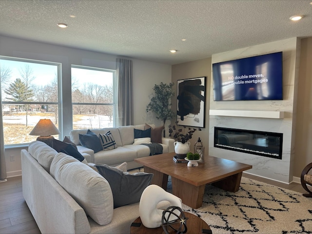 living room with a fireplace, recessed lighting, a textured ceiling, wood finished floors, and baseboards