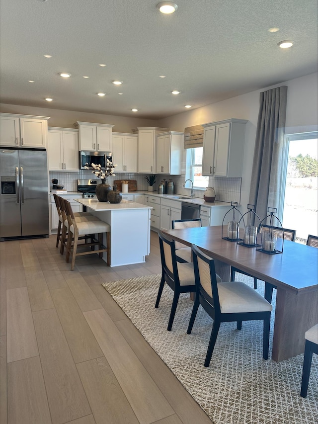 kitchen featuring a center island, stainless steel appliances, tasteful backsplash, light countertops, and a healthy amount of sunlight