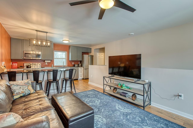 living area with baseboards, ceiling fan, and light wood-style floors