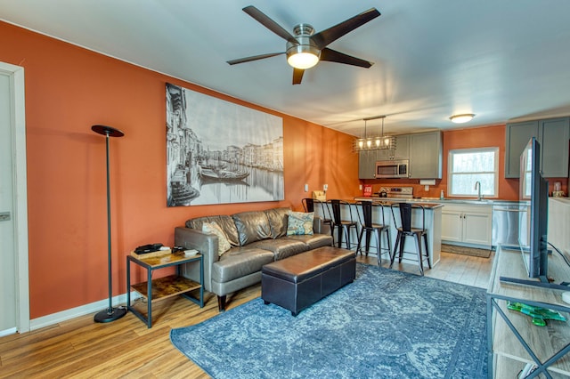 living room featuring light wood finished floors, ceiling fan, and baseboards