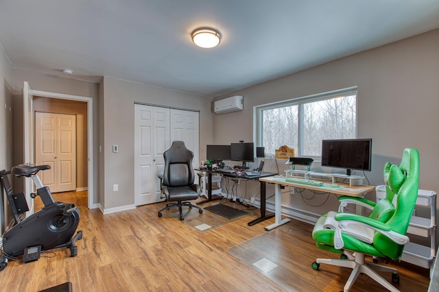 office space with a wall unit AC, wood finished floors, and baseboards