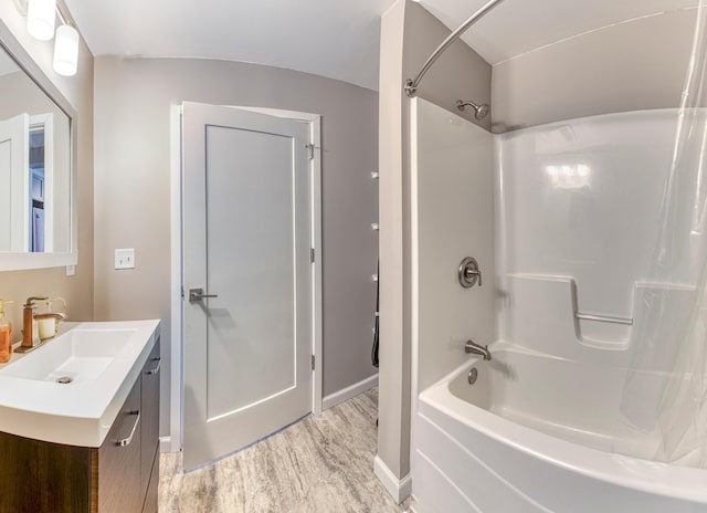 full bath featuring  shower combination, wood finished floors, vanity, and baseboards