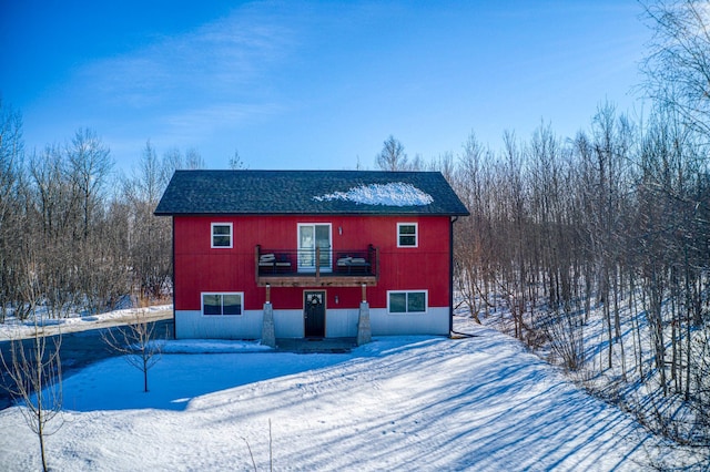 snow covered house featuring roof with shingles