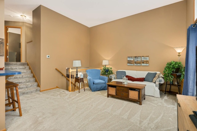 sitting room with carpet floors, baseboards, stairway, and an upstairs landing