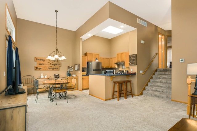 kitchen with visible vents, a high ceiling, light carpet, and freestanding refrigerator