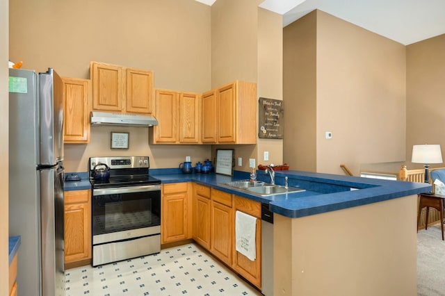 kitchen featuring dark countertops, appliances with stainless steel finishes, a peninsula, under cabinet range hood, and a sink