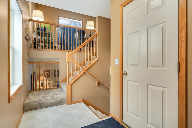 stairway featuring carpet floors, baseboards, and tile patterned floors