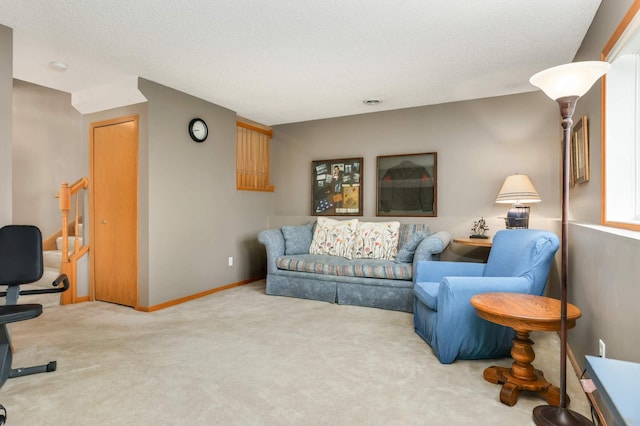 carpeted living area featuring a textured ceiling, baseboards, and stairs