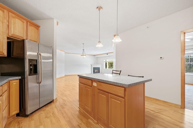 kitchen featuring a glass covered fireplace, stainless steel fridge, a center island, and light wood-type flooring