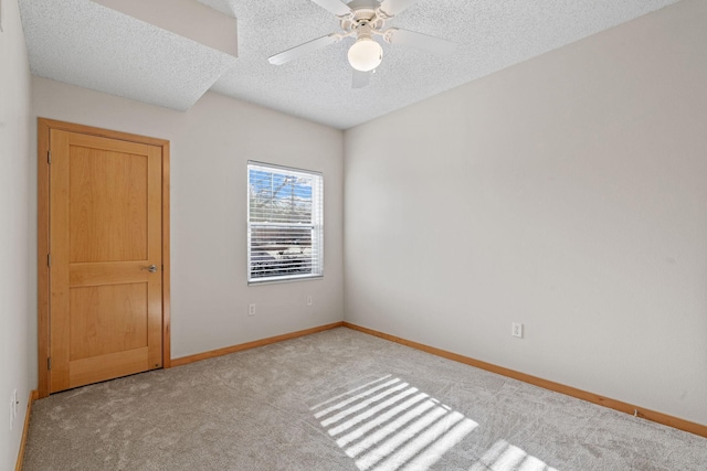 carpeted spare room with a ceiling fan, baseboards, and a textured ceiling