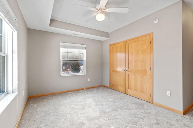 unfurnished bedroom featuring a ceiling fan, a textured ceiling, a closet, carpet flooring, and baseboards