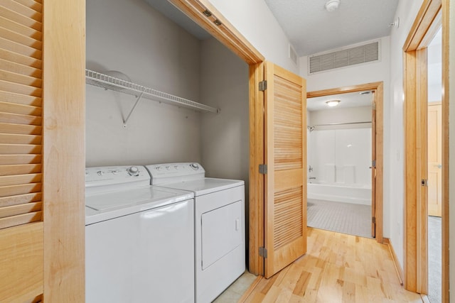 laundry area with visible vents, light wood-type flooring, laundry area, washer and dryer, and a textured ceiling