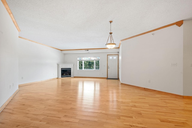 unfurnished living room with baseboards, light wood-type flooring, ornamental molding, a glass covered fireplace, and a textured ceiling