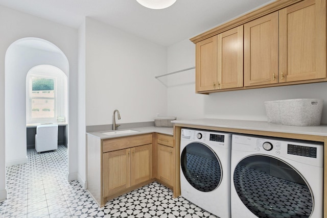 laundry area featuring a sink, washing machine and clothes dryer, cabinet space, and baseboards