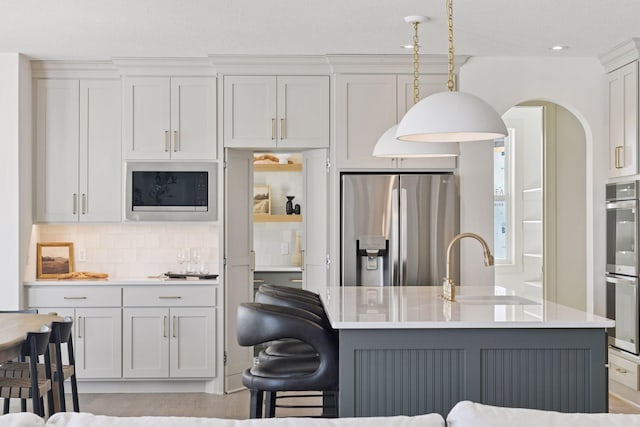 kitchen with stainless steel appliances, light countertops, a sink, and tasteful backsplash