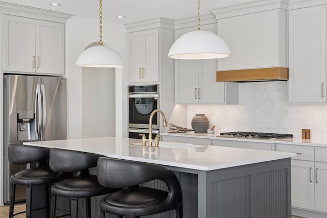 kitchen with stainless steel appliances, tasteful backsplash, light countertops, custom range hood, and a sink