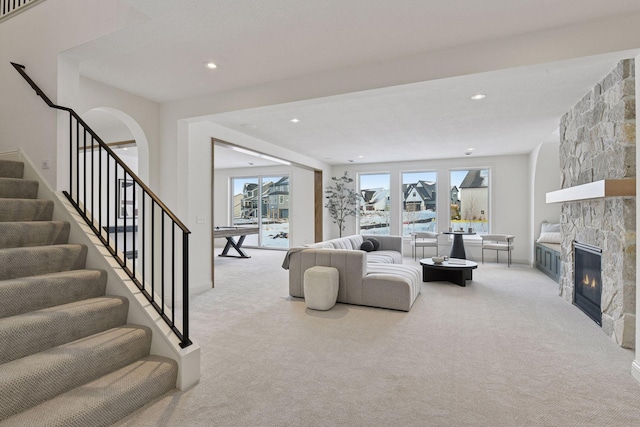 living area with stairway, recessed lighting, carpet flooring, and a stone fireplace