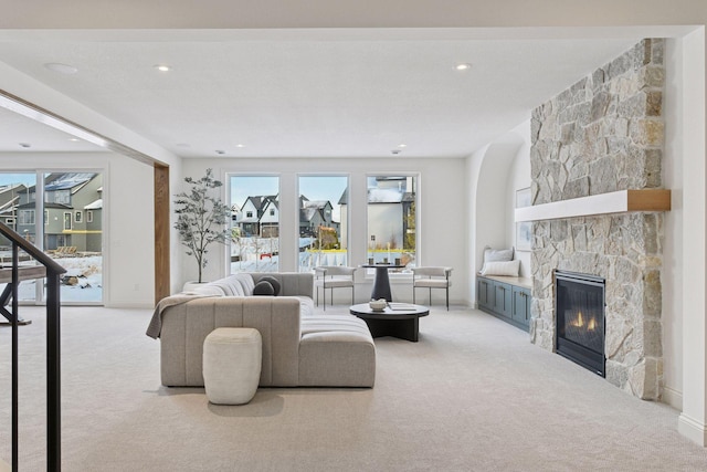 living area featuring carpet floors, a stone fireplace, and baseboards