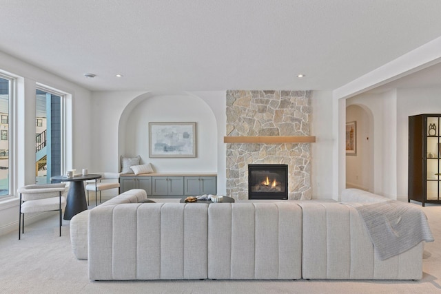 living area with baseboards, arched walkways, light colored carpet, a fireplace, and recessed lighting