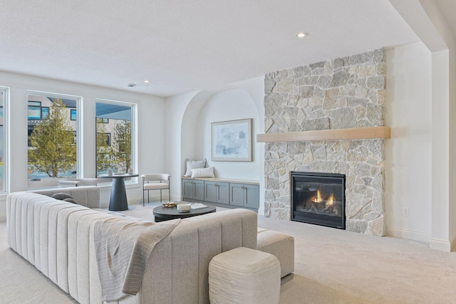 carpeted living area featuring recessed lighting, baseboards, and a stone fireplace