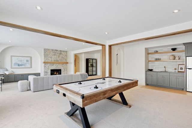 recreation room with recessed lighting, a fireplace, a sink, and light colored carpet