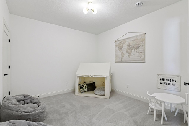 playroom featuring a textured ceiling, carpet, visible vents, and baseboards