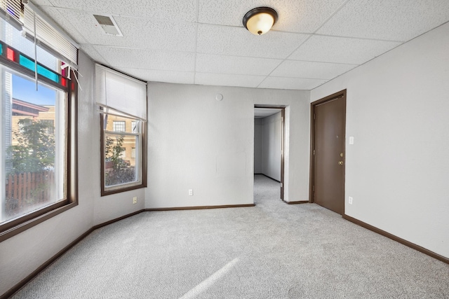 carpeted empty room featuring a drop ceiling, visible vents, and baseboards