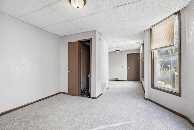 spare room with a paneled ceiling, carpet, visible vents, and baseboards