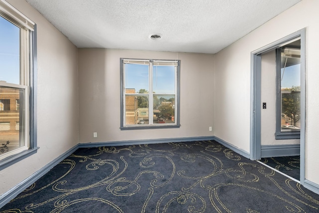 empty room with carpet, visible vents, and baseboards