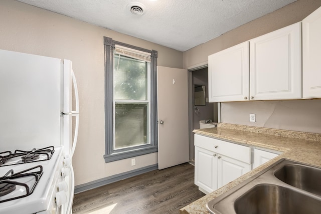 kitchen featuring white appliances, dark wood-style floors, visible vents, and white cabinets