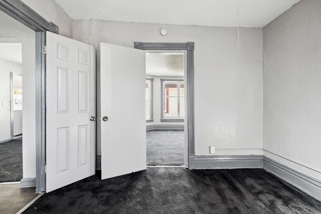 carpeted spare room with a textured ceiling and a textured wall